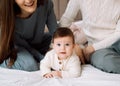 Young family with a baby, lie on the bed, have fun. Concept of childhood, love and family. Royalty Free Stock Photo