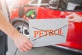 Young family buying first electric car in the showroom. No gasoline. Close-up of hands holding paper with word Petrol on