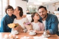 Dad and the little son are giving flowers to mother and daughter in a cafe. Royalty Free Stock Photo