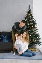 Family celebrates Christmas at home in the living room near the Christmas tree. Happy mom, dad and son enjoy their vacation togeth Royalty Free Stock Photo