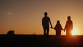 Young family with a child admiring the sunset in the field, holding hands Royalty Free Stock Photo