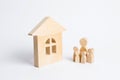 A young family with children is standing near a wooden house. The concept of a strong family, the continuation of the family.