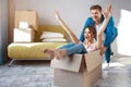 Young family couple bought or rented their first small apartment. Cheerful happy people having fun. She sit in box and