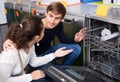 Young family couple choosing new dish washing machine in superm Royalty Free Stock Photo