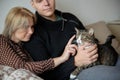 Young family couple with domestic cat and tea cup on sofa at home Royalty Free Stock Photo