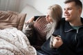 Young family couple with domestic cat and tea cup on sofa at home Royalty Free Stock Photo