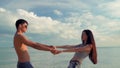 Young family, couple man and woman active spinning holding hands. background sea or ocean, laughing holding hands. Summer Theme