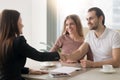 Young family couple meeting with broker, handshake symbolizing a
