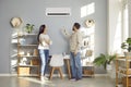 Young family couple setting up the temperature on the air conditioner in the living room Royalty Free Stock Photo