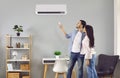Young family couple setting up the temperature on a modern air conditioner at home Royalty Free Stock Photo