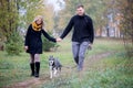 Happy young family couple with siberian husky dog walking in autumn park Royalty Free Stock Photo