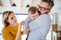 A young family with a crying toddler girl standing indoors at home. Royalty Free Stock Photo