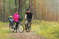 Young family cycling on forest trail with kid in bike child seat. active sports outdoor recreation