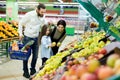 A young family with a daughter choose apples in the vegetable Department in the supermarket. Royalty Free Stock Photo