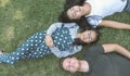 Young family with daughter laying in the park on the green grass and looking at the camera, top view Royalty Free Stock Photo