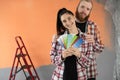 Young family doing painting wall during home renovation. Woman holding multi color palette with paint samples Royalty Free Stock Photo