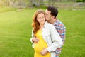 Young family is expecting a baby. Happy couple of parents-to-be walking together. Handsome man hugging and kissing of pregnant Royalty Free Stock Photo