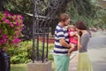 Young family of father mother and baby child daughter walking and holding each other on summer city street park close to bouquet o Royalty Free Stock Photo