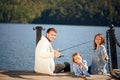 Happy family with daughter fishing in pond in fall Royalty Free Stock Photo