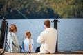 Happy family with daughter fishing in pond in fall Royalty Free Stock Photo