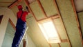 house attic insulation - construction worker installing rock wool in mansard wall