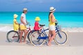 Young family of four riding bicycles on a tropical sand beach Royalty Free Stock Photo