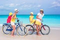 Young family of four riding bicycles on a tropical sand beach Royalty Free Stock Photo