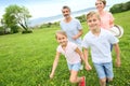 Young family of four running on green grass