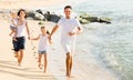 Young family of four running on sandy beach Royalty Free Stock Photo