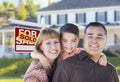 Young Family in Front of Sold Real Estate Sign and House Royalty Free Stock Photo