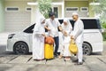 Young family and grandparents standing near the car