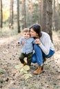 Young family, happy woman mom having fun in autumn pine forest with her child little son. Mother hugging her kid son Royalty Free Stock Photo