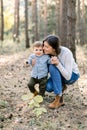 Young family, happy woman mom having fun in autumn pine forest with her child little son. Mother hugging her kid son Royalty Free Stock Photo