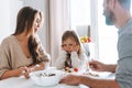 Young family has lunch at table in bright kitchen at home. The daughter does not want to eat and parents worried Royalty Free Stock Photo