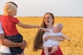 Young family having fun ourdoors. Mom dad and two kids in wheat field. Lifestyle