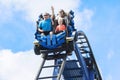 Young family having fun riding a rollercoaster at a theme park