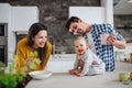 A young family at home, a man holding a baby and a woman feeding her. Royalty Free Stock Photo