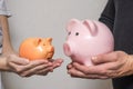 A young family husband and wife are holding piggy banks of different sizes showing the level of their contribution to the family Royalty Free Stock Photo