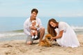 Young family with a infant and dog relax on the beach Royalty Free Stock Photo