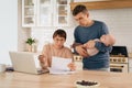 Young family with little baby using laptop in kitchen Royalty Free Stock Photo