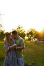 Young family mom dad walking in the evening in a Park with trees in the sunset light. Couple kissing. Happy young couple Royalty Free Stock Photo