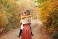 Young family, mother and little son, on walk in autumn forest, mom and child holding hands and walking along path covered with Royalty Free Stock Photo