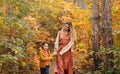 Young family, mother and little son, on walk in autumn forest, mom and child holding hands and walking along path covered with Royalty Free Stock Photo