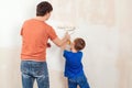 Young family painting house wall. Father and son painting a wall. Happy family renovating their new home Royalty Free Stock Photo