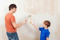 Young family painting house wall. Father and son painting a wall. Happy family renovating their new home Royalty Free Stock Photo