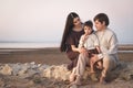 Young family of 3 people spend time together on the beach. Family look linen clothes