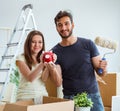 Young family with piggybank unpacking at new house with boxes
