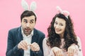 Young family on pink background. Easter Happy couple. Holiday. A tiny ear. People from the rabbit ears. Dodge doing Royalty Free Stock Photo