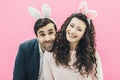 Young family on pink background. Easter Happy couple. Holiday. A tiny ear. People from the rabbit ears. Get rid of Royalty Free Stock Photo