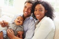 Young Family Playing With Happy Baby Son At Home